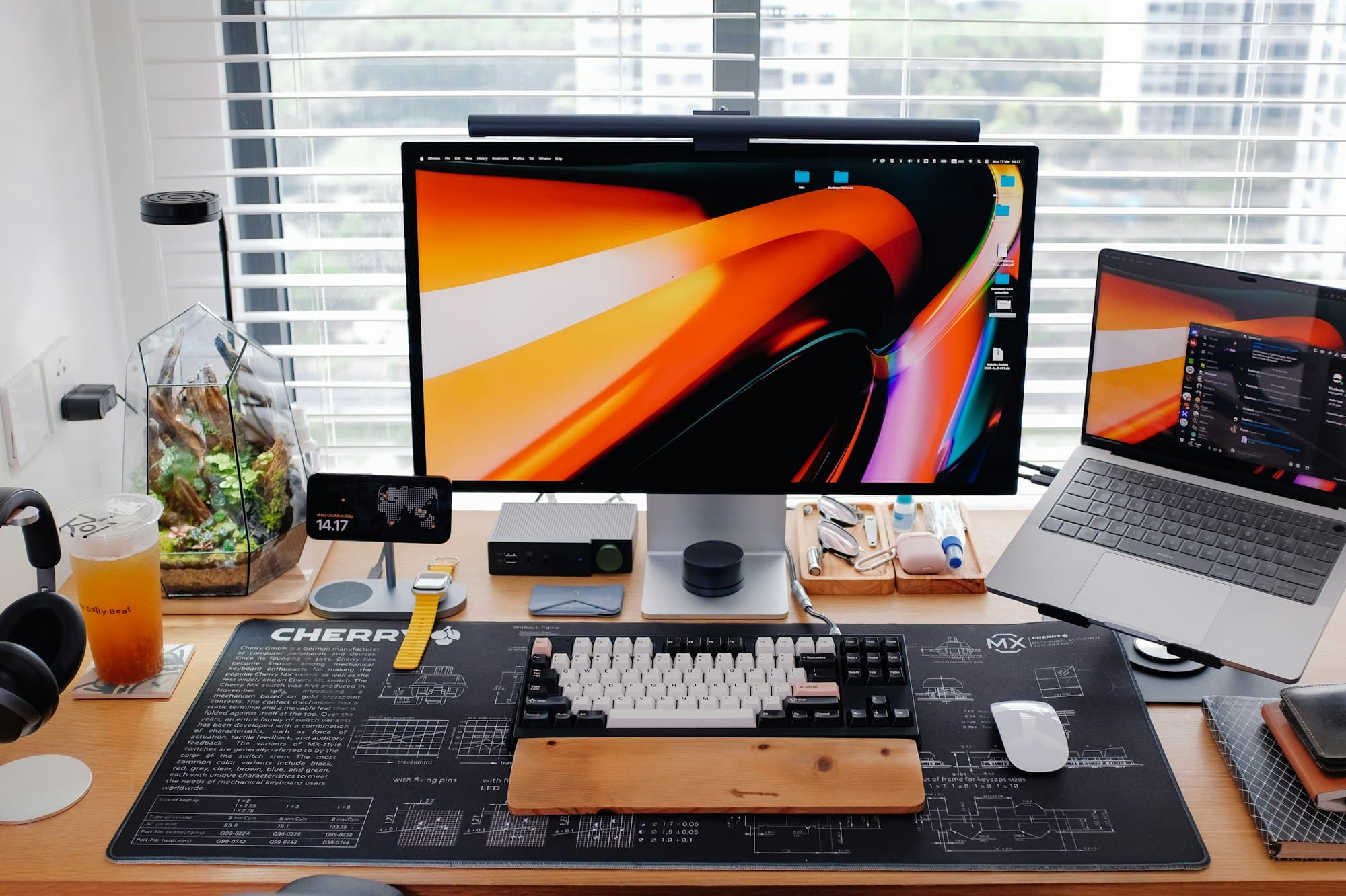 Un poste de travail en ordre : un grand écran, un ordinateur portable sur un support, un clavier et une souris sur un sous-main.