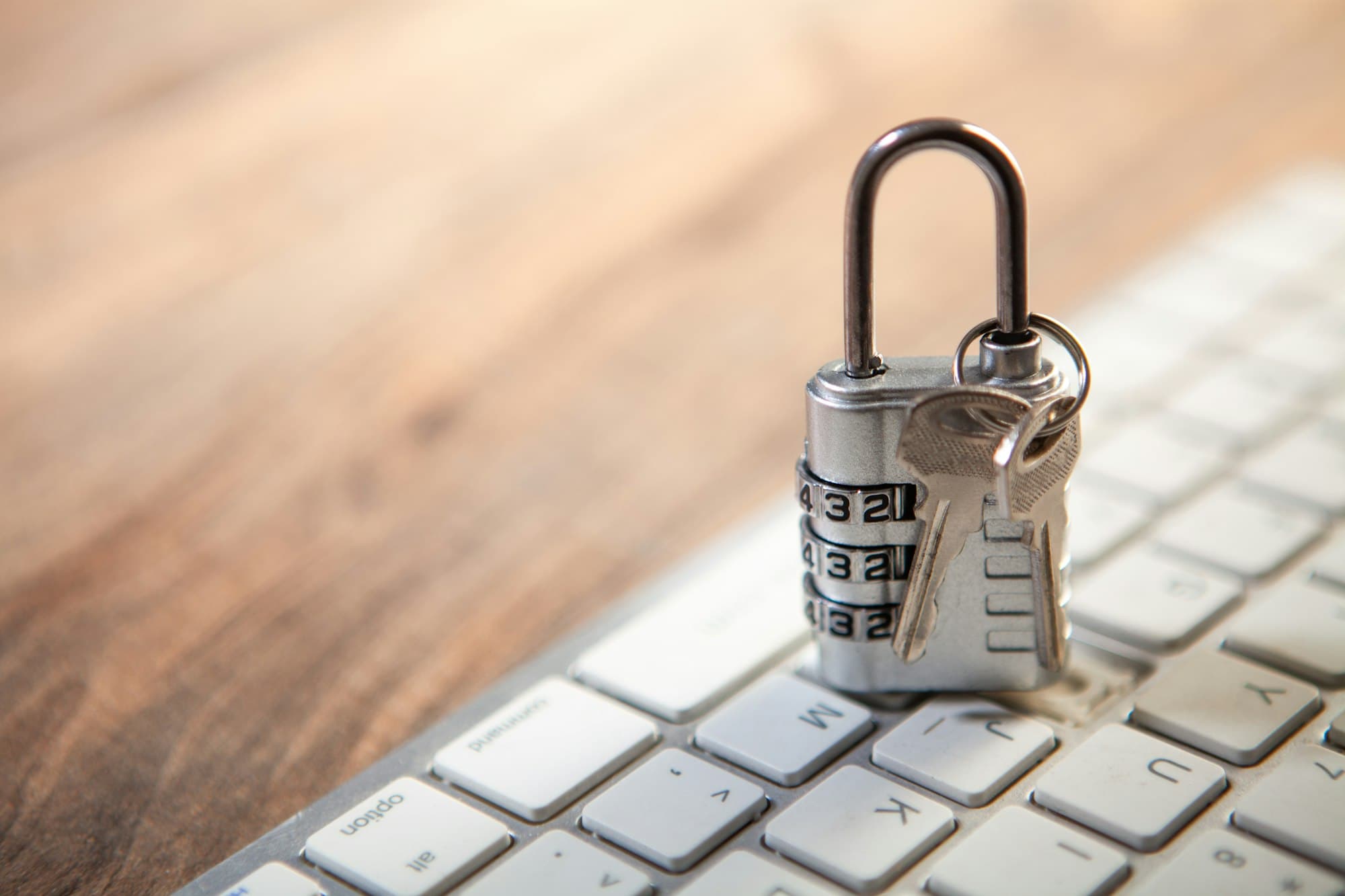 Un cadenas à code fermé, avec ses clés, posé sur le clavier d'un ordinateur.