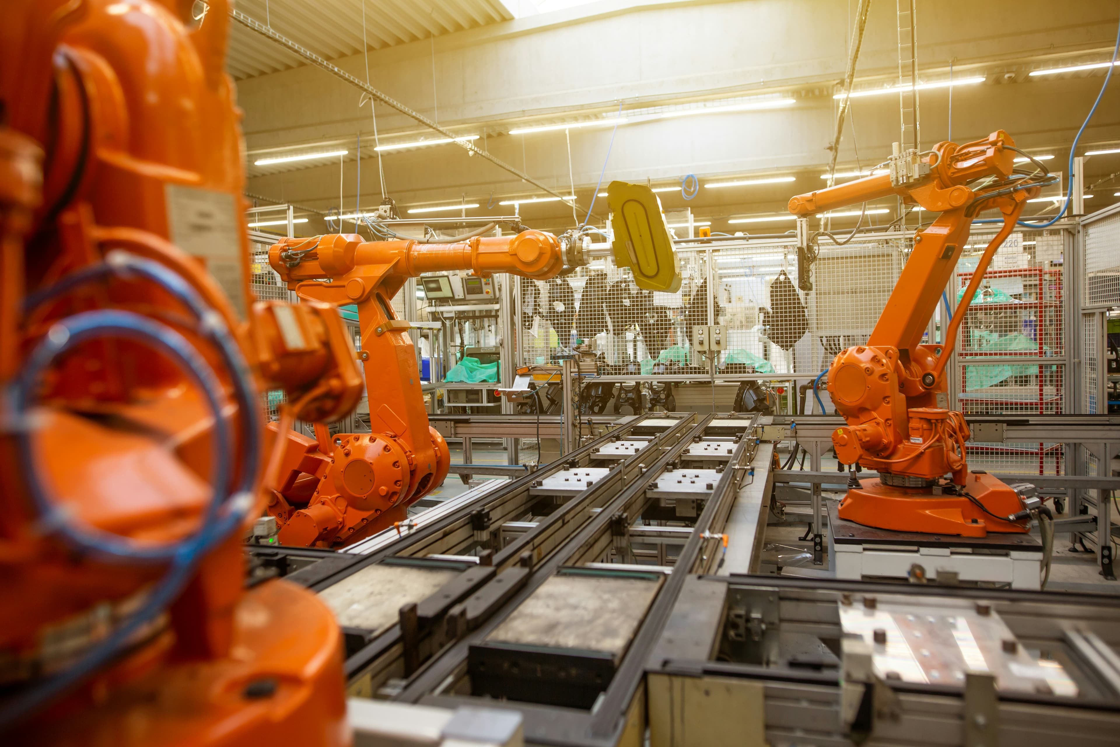 Des bras robotisés orange sur une chaîne d'assemblage automatisée.